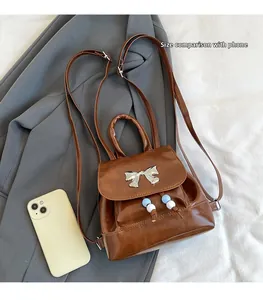 Brown mini butterfly backpack with beads compared to a smartphone for size reference