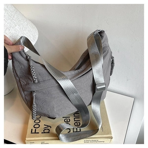 Détail du sac demi-lune en nylon gris avec tissu texturé et tirette de zip tissée