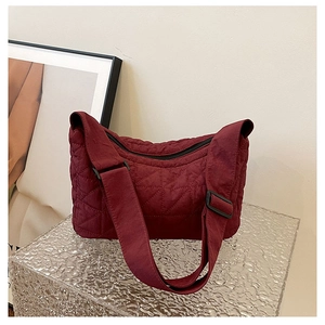 Detail of burgundy quilted tote bag with padded strap and adjustable buckle closure