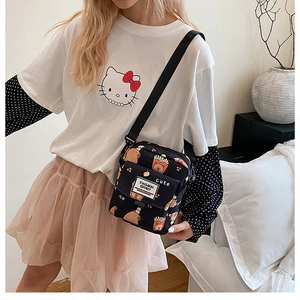 Détail d'un sac bandoulière en toile noire avec des imprimés de dessins animés et une sangle