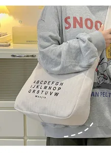 Close-up of cream canvas tote bag with black alphabet letter print and sturdy strap