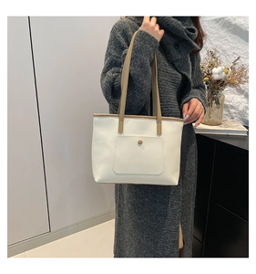 Detailed close-up of a minimalist cream tote bag with khaki straps worn by a model