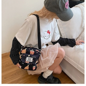 Détail du petit sac bandoulière noir avec motifs de dessins animés et sangle réglable