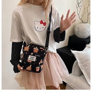 Détail du sac bandoulière en toile noire avec motifs de dessins animés mignons