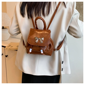 On-body view of a caramel brown mini backpack with silver butterfly bow and bead details