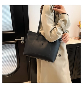 Detail of minimalist black leather tote bag with flap pocket and round magnetic snap button