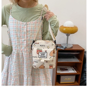 Détail du sac bandoulière en toile avec motif ours porté par un mannequin femme