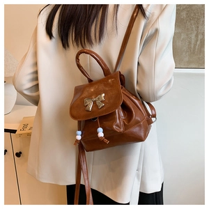 Detail of a dark brown vintage leather mini backpack with a silver metal butterfly bow