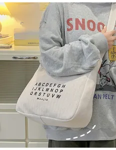 Detail of cream canvas tote bag with black alphabet print and wide shoulder strap