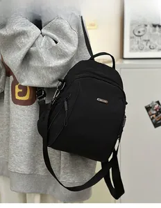 Side view of a compact black nylon backpack with metal logo and fabric straps on a model
