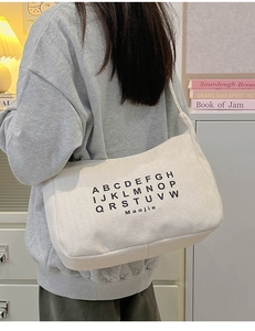 Detail of herringbone canvas fabric and letter print on stylish off-white tote bag