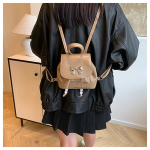 Detail of khaki mini backpack with silver butterfly buckle and beaded drawstring charms
