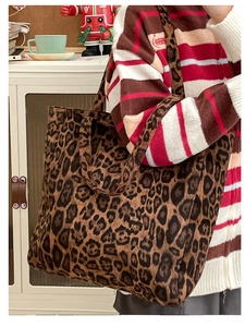 Large leopard print canvas tote bag carried over the shoulder by a model in casual wear