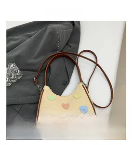 Close-up of beige woven underarm bag featuring colorful heart patches and brown leather trim
