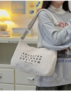 Detail of beige corduroy hobo bag with adjustable strap and casual letter print