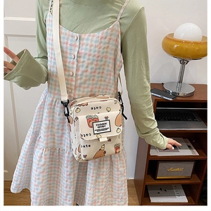 Détail du joli sac bandoulière en toile beige avec imprimés cartoon et sangle réglable