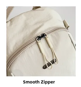 Detailed close-up of the beige nylon backpack featuring smooth double zippers and JING PIN tag