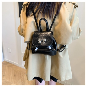 Close-up of black leather butterfly backpack with silver bow and pearl drawstring detail