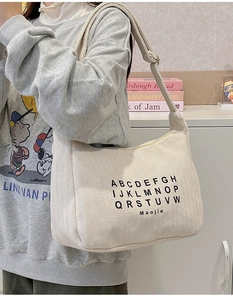 Detail of off-white canvas tote bag featuring herringbone texture and adjustable strap