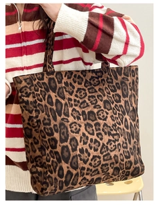 Detail view of a large leopard print tote bag with thick plush texture on model shoulder