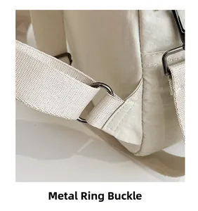 Close-up of durable gunmetal hardware rings and reinforced nylon strap on beige backpack