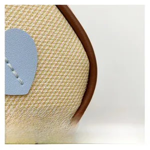 Detail of yellow woven fabric with brown leather trim and blue heart-shaped patch