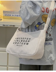 Detail of white corduroy hobo bag with letter print and adjustable wide shoulder strap