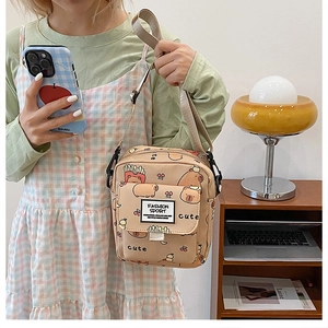 Détail du sac à bandoulière en toile beige avec imprimé capybara et sangle réglable