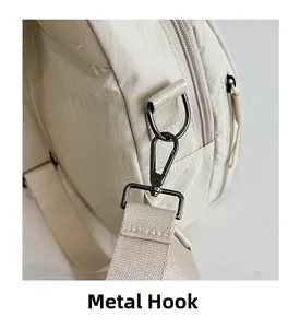 Detail of durable matte grey hardware hook and thick woven strap on beige nylon backpack