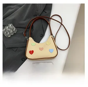 Detail view of woven beige bag featuring colorful heart patches and brown leather strap