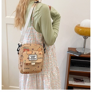 Détail du sac bandoulière en toile avec imprimés cartoon et sangle réglable
