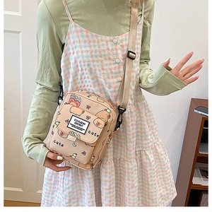 Gros plan du sac bandoulière beige avec imprimés cartoons et étiquette Fashion Sport