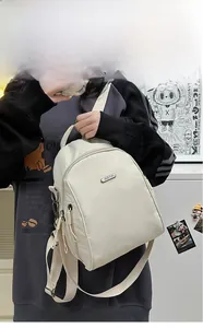 Detail view of cream white nylon backpack with adjustable straps and metal zip closure