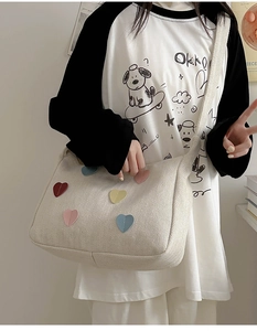 Detailed macro view of cream canvas tote bag featuring colorful leather heart patches