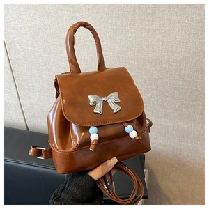 Close-up of brown faux leather mini backpack with silver butterfly bow and colorful beads