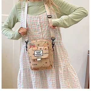 Détail du sac bandoulière en toile beige avec motifs de capybara et sangle réglable