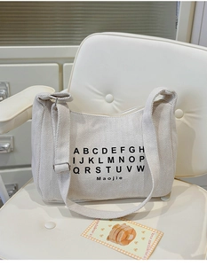 Detailed close-up of herringbone weave canvas on off-white tote bag with black letter print