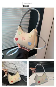 Detailed close-up of beige woven bag with colorful heart patches and silver strap