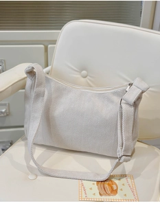 Detail of off-white canvas crossbody bag showing herringbone texture and silver zipper