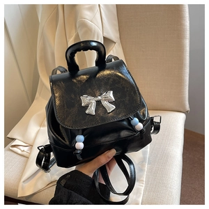 Close-up of black PU leather mini backpack featuring silver butterfly and beaded drawstrings