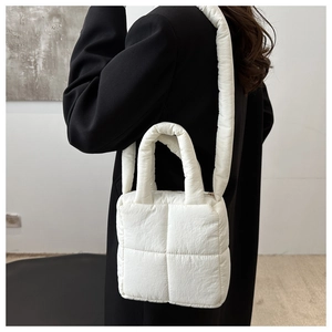 Bolso acolchado blanco moderno sobre un abrigo negro para un look de moda minimalista