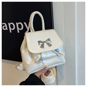 Macro shot of a cream PU leather backpack featuring a silver butterfly bow and colorful beads