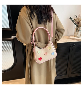 Lifestyle shot of a beige canvas underarm bag with colorful heart patches and pink straps