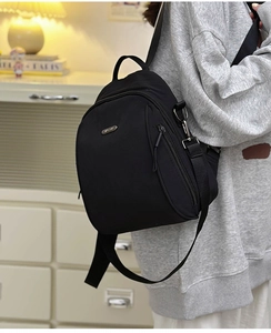 Detail of minimalist black nylon mini backpack with adjustable strap and side pocket