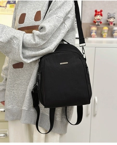 Side view of black nylon backpack with silver logo and adjustable wide fabric straps
