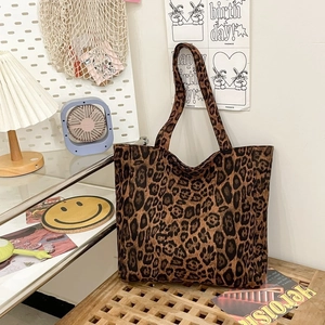 Large leopard print tote bag with wide straps on a wooden table in a cozy home setting