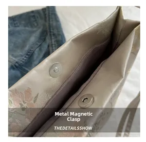 Detailed macro view of secure double magnetic metal clasps on embroidered handbag