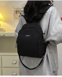 Close-up of minimalist black nylon mini backpack with adjustable straps and metal logo