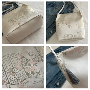Detailed embroidery on off-white satin bag with floral patterns and grey tassel accent