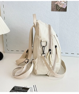 Detail view of cream white nylon backpack showing side zippers and adjustable straps